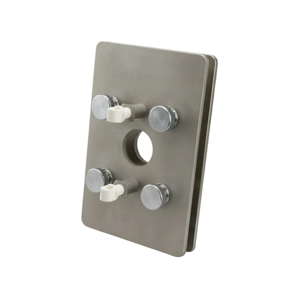 A square metallic industrial component with a brushed silver-gray finish, featuring four threaded ports with white plastic caps and a circular cutout in the center, photographed on a light gray studio background.
