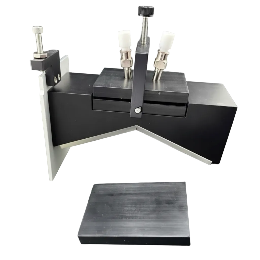 A black and silver scientific sample stage or microtome component with white knobs, shown on a dark gray background with a separate black metal base piece in front.