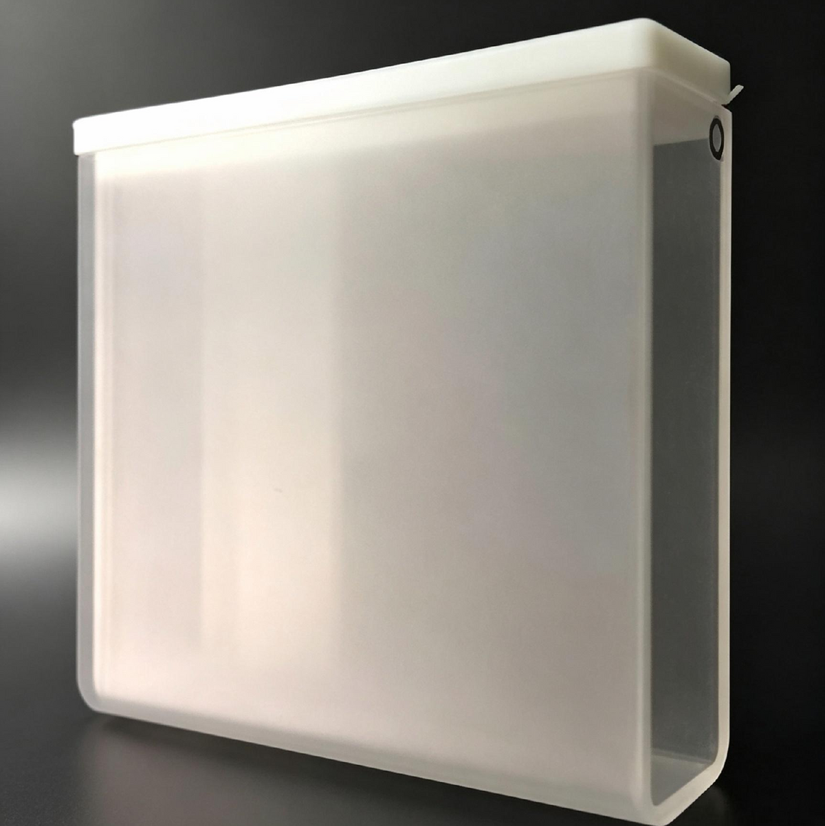 A translucent frosted white plastic square box with a hinged side panel, shown on a dark gray background.