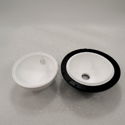 Two white plastic bowl-shaped components, one plain and one with a black outer rim, shown on a light gray textured background.